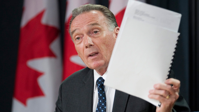 Minister of the Environment Peter Kent holds up a copy of a report as he announces plans for integrated oil sands monitoring during a news conference in Ottawa, Thursday July 21, 2011. (Adrian Wyld / THE CANADIAN PRESS)